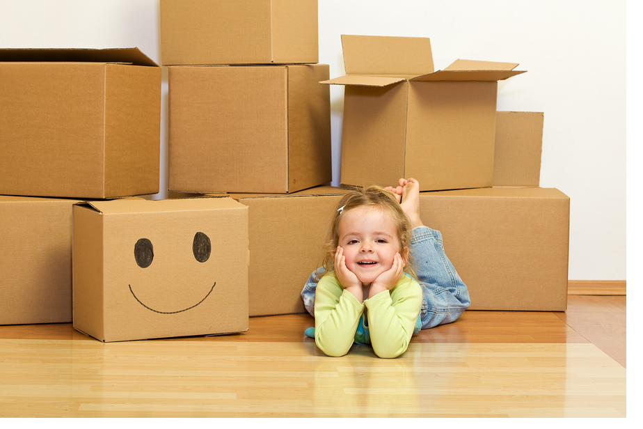 Smiling little girl next to moving boxes at home